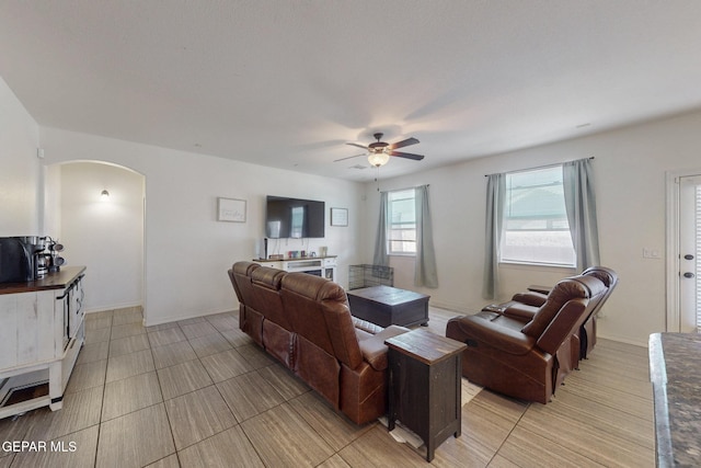 living area featuring arched walkways and a ceiling fan