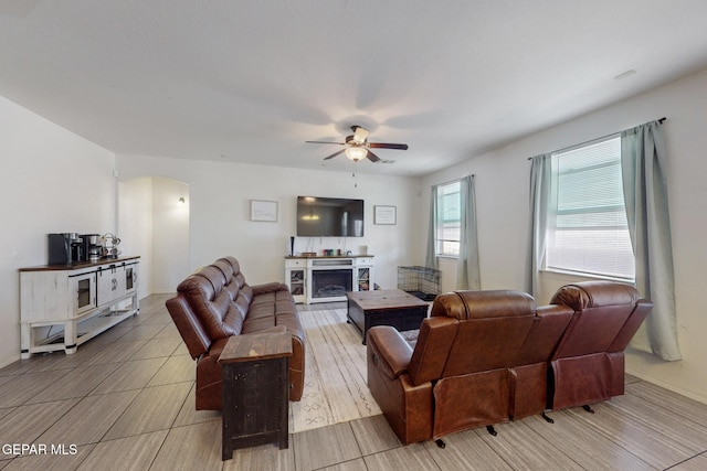 living room featuring a ceiling fan, baseboards, and arched walkways