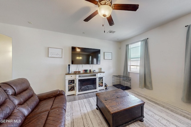 living room featuring wood finished floors, visible vents, arched walkways, and ceiling fan