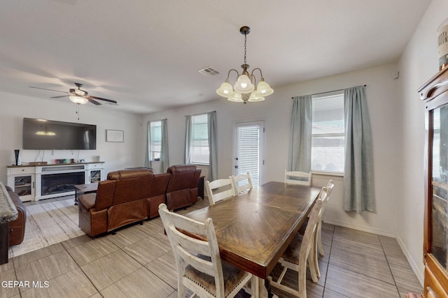 dining area with baseboards, visible vents, ceiling fan with notable chandelier, a fireplace, and light tile patterned floors