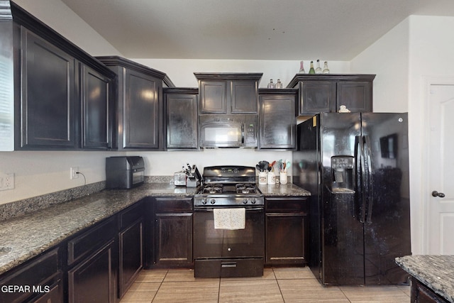 kitchen featuring dark stone counters, black appliances, and light tile patterned floors