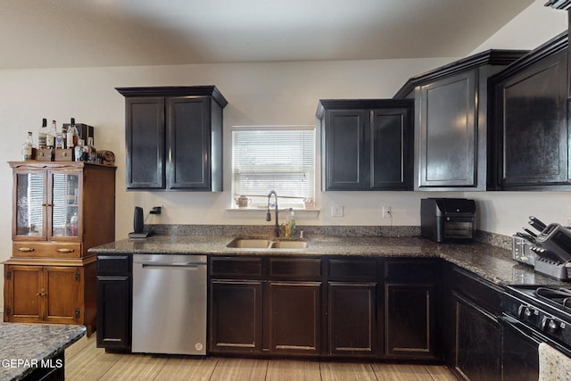 kitchen featuring dark countertops, dishwasher, light wood-style floors, and a sink