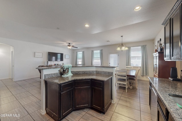 kitchen featuring ceiling fan with notable chandelier, a wealth of natural light, dark brown cabinetry, and arched walkways