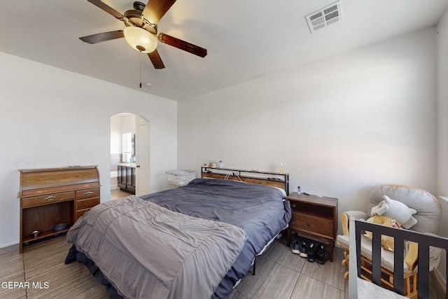bedroom featuring wood finished floors, visible vents, arched walkways, and ceiling fan