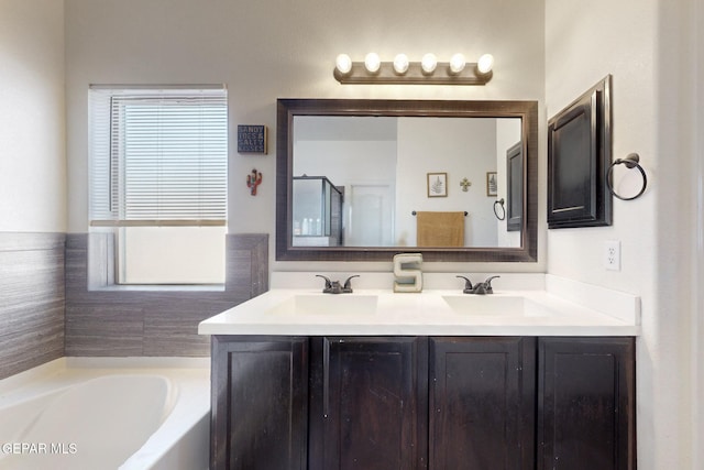 bathroom with double vanity, a bath, and a sink