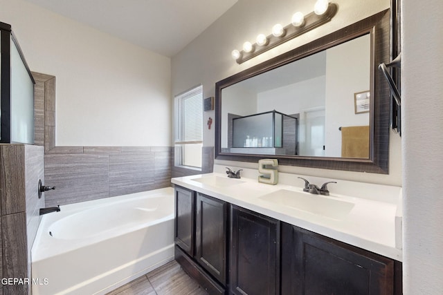 bathroom with double vanity, a garden tub, a stall shower, and a sink
