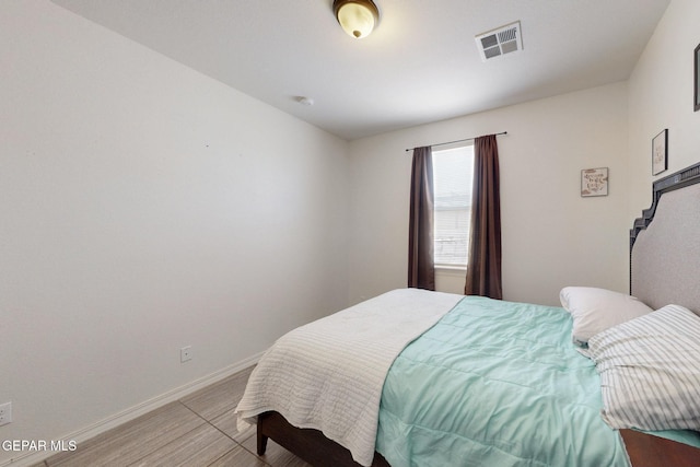 bedroom featuring baseboards, light wood finished floors, and visible vents