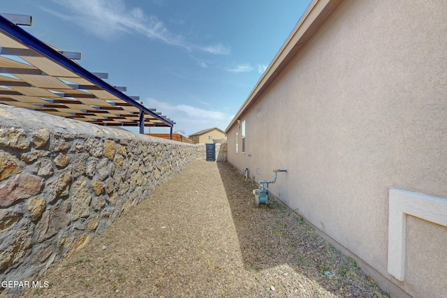 view of side of home with stucco siding and fence