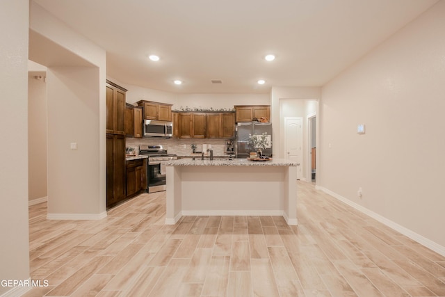 10716 Drew Pearson Dr, El Paso, TX 79924 - kitchen with a center island, tasteful backsplash, appliances with stainless steel finishes, and light wood-style flooring