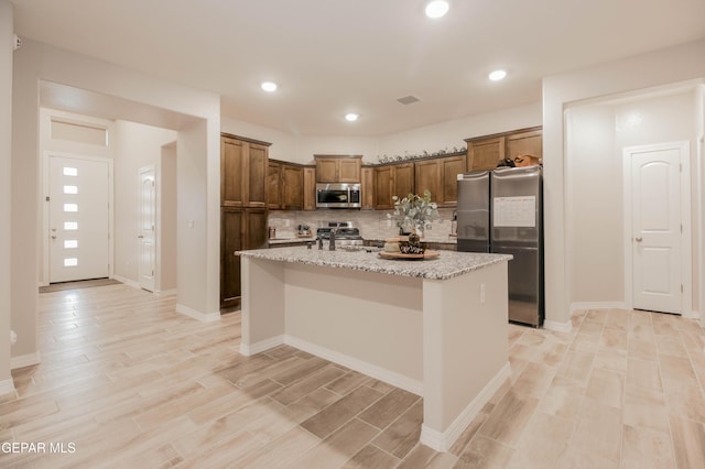 10716 Drew Pearson Dr, El Paso, TX 79924 - kitchen featuring a center island, tasteful backsplash, a sink, stainless steel appliances, and light wood-style flooring