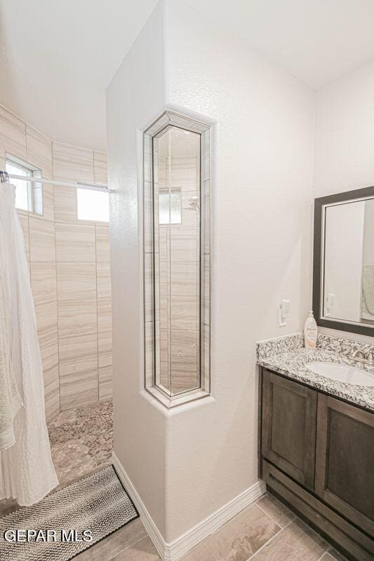 10716 Drew Pearson Dr, El Paso, TX 79924 - full bath featuring baseboards, vanity, and a tile shower