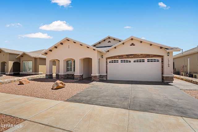 mediterranean / spanish home with concrete driveway, a garage, stone siding, and stucco siding