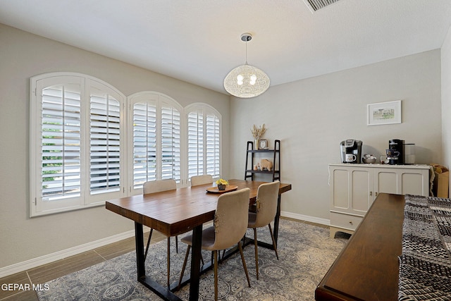 dining area with baseboards, visible vents, and an inviting chandelier