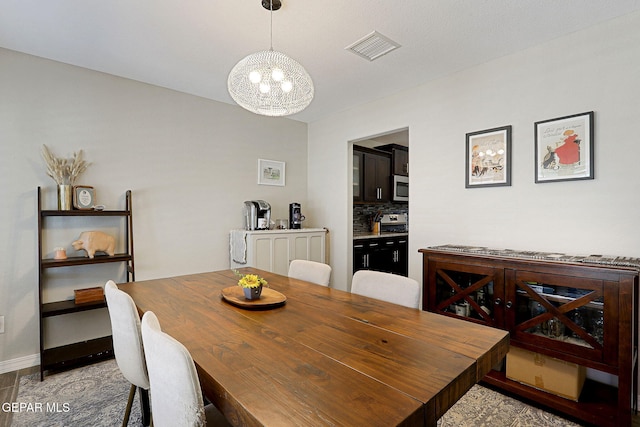 dining area featuring baseboards, a chandelier, and visible vents