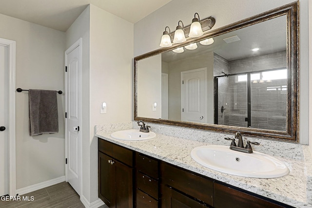 bathroom with a sink, a shower stall, double vanity, and visible vents