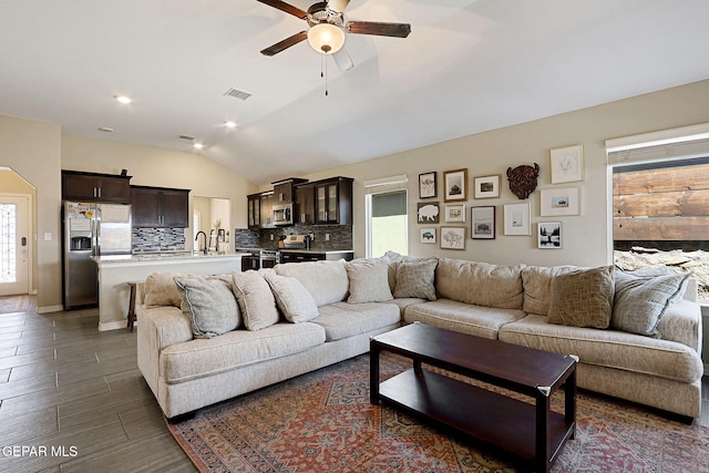 living room featuring vaulted ceiling, a ceiling fan, dark wood-type flooring, and visible vents