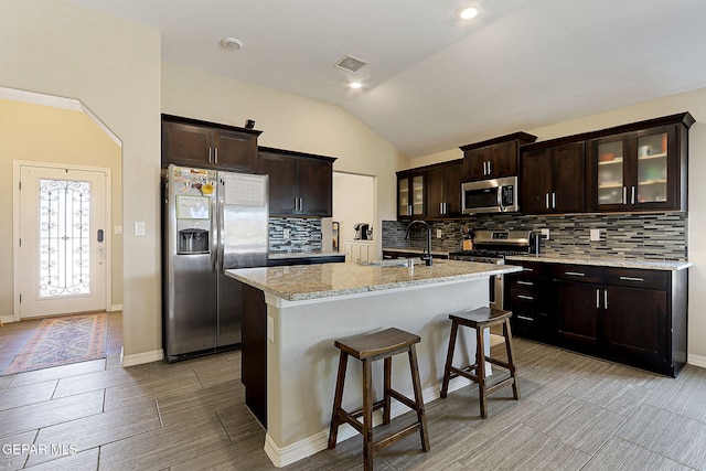 kitchen with stainless steel appliances, vaulted ceiling, decorative backsplash, and a sink