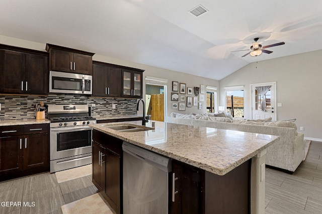 kitchen with a sink, stainless steel appliances, a ceiling fan, lofted ceiling, and tasteful backsplash