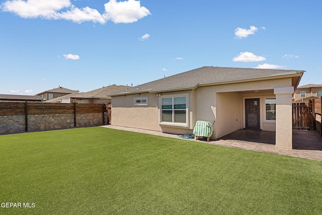 back of property featuring roof with shingles, a fenced backyard, a yard, a patio, and stucco siding
