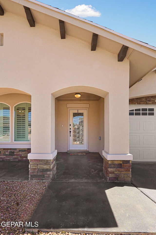 entrance to property featuring a garage and stucco siding