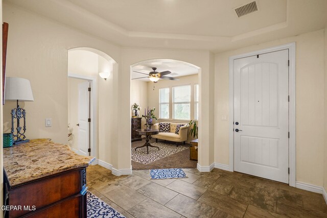 foyer featuring arched walkways, visible vents, and a raised ceiling
