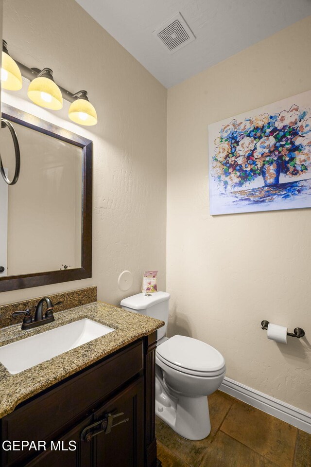 half bathroom with baseboards, visible vents, toilet, and vanity
