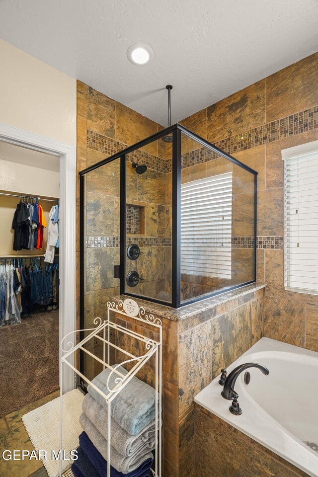 full bath with a walk in closet, a bath, and a shower stall