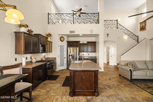 kitchen featuring ceiling fan, stainless steel refrigerator with ice dispenser, stone tile floors, and gas stove