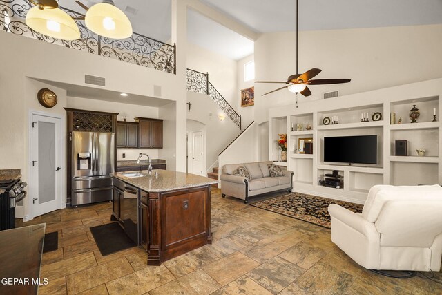 living area with visible vents, a ceiling fan, and a high ceiling