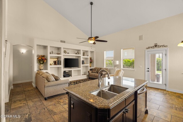 kitchen with stainless steel dishwasher, a sink, arched walkways, baseboards, and high vaulted ceiling