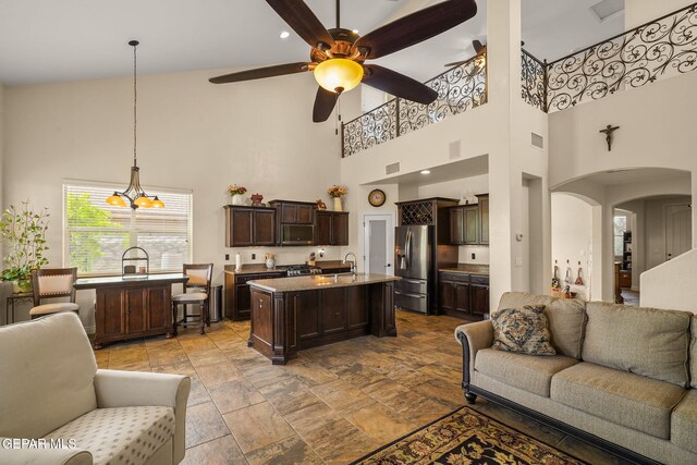 living area with arched walkways, visible vents, a high ceiling, and ceiling fan with notable chandelier