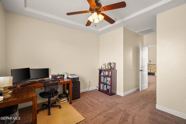carpeted office featuring a raised ceiling, visible vents, a ceiling fan, and baseboards