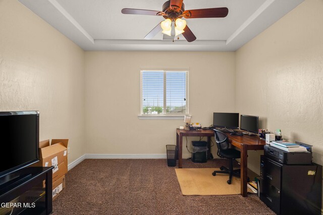 office area featuring a raised ceiling, carpet flooring, baseboards, and ceiling fan