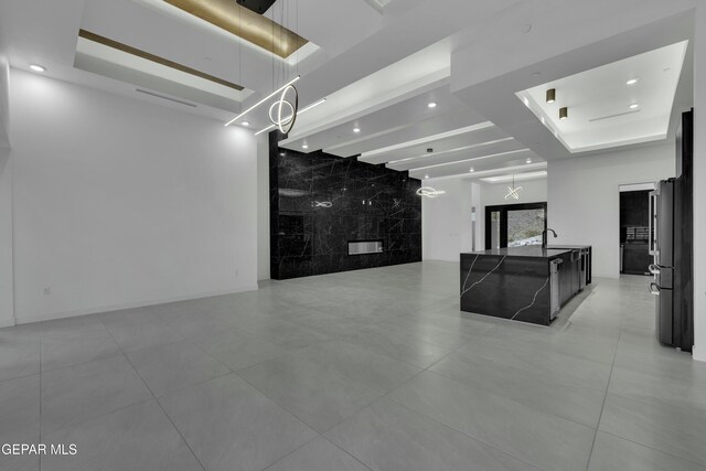 interior space featuring a sink, a tray ceiling, recessed lighting, and light tile patterned floors