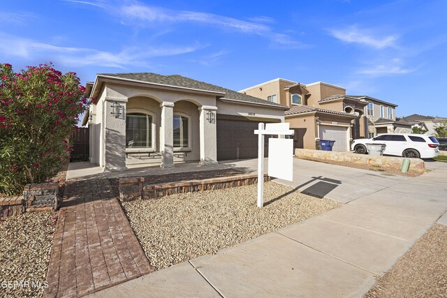 14218 Charles Pollock Ave, El Paso, TX 79938 - view of front of home with an attached garage, stucco siding, covered porch, and concrete driveway
