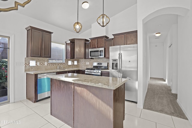 14218 Charles Pollock Ave, El Paso, TX 79938 - kitchen with appliances with stainless steel finishes, dark brown cabinetry, arched walkways, tasteful backsplash, and a center island
