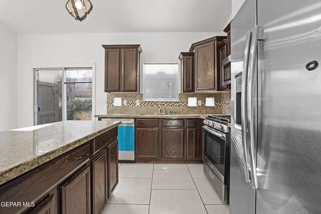 14218 Charles Pollock Ave, El Paso, TX 79938 - kitchen featuring stainless steel appliances, tasteful backsplash, light stone counters, light tile patterned flooring, and dark brown cabinets