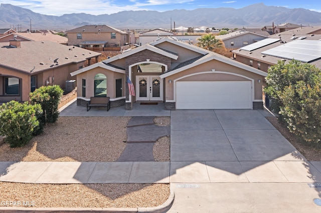 view of front of house with french doors, a mountain view, stucco siding, and a garage