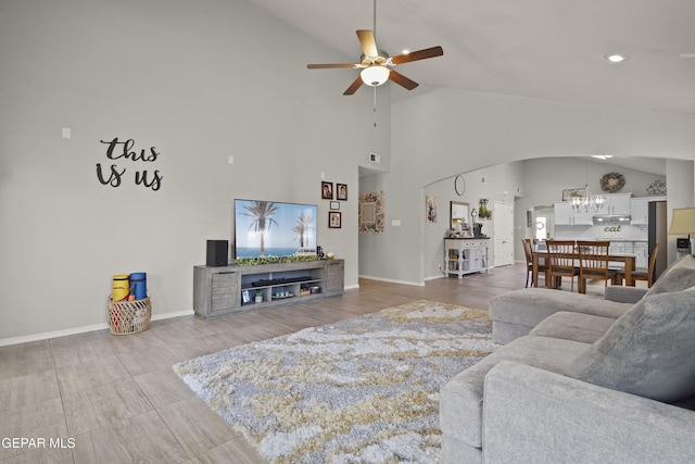 living room featuring a ceiling fan, arched walkways, high vaulted ceiling, baseboards, and wood finished floors