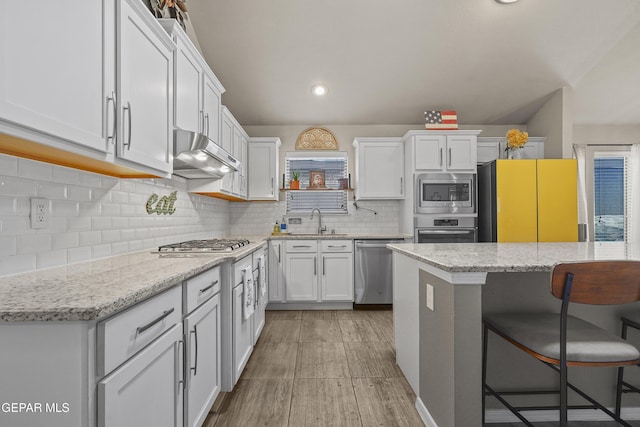kitchen with stainless steel appliances, a sink, a kitchen breakfast bar, white cabinets, and recessed lighting