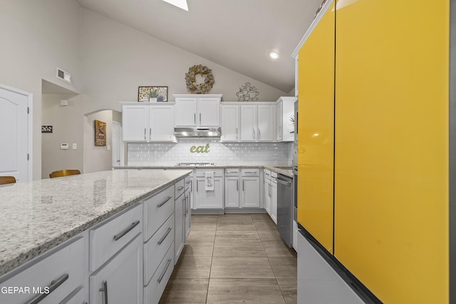 kitchen with under cabinet range hood, tasteful backsplash, white cabinetry, appliances with stainless steel finishes, and high vaulted ceiling