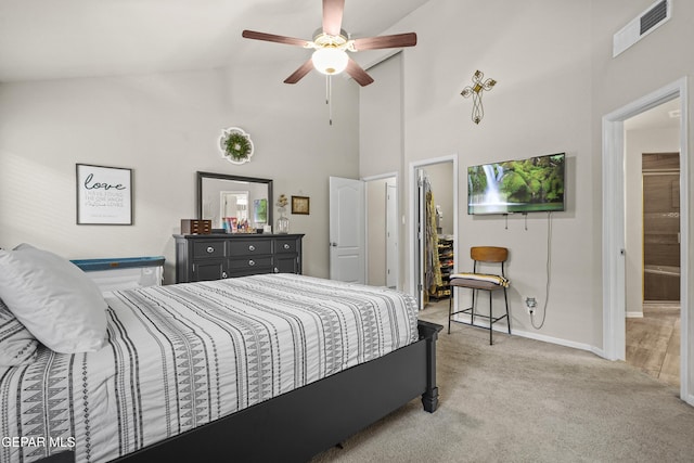 bedroom with light colored carpet, high vaulted ceiling, baseboards, a walk in closet, and a ceiling fan