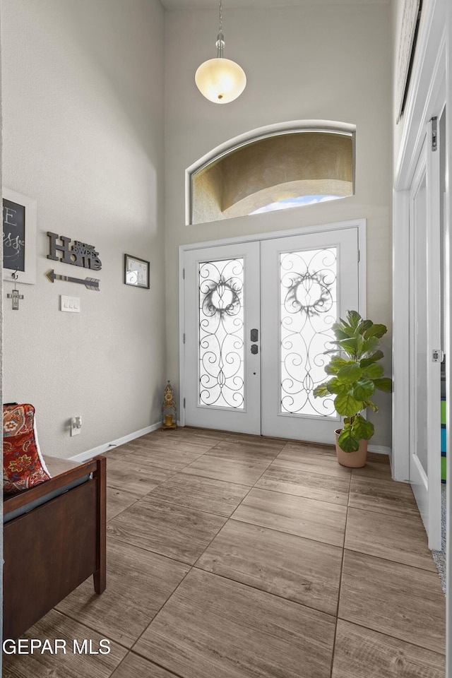 entrance foyer with a high ceiling, french doors, and baseboards
