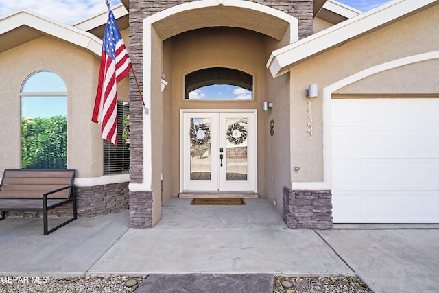 doorway to property featuring stucco siding, stone siding, and french doors