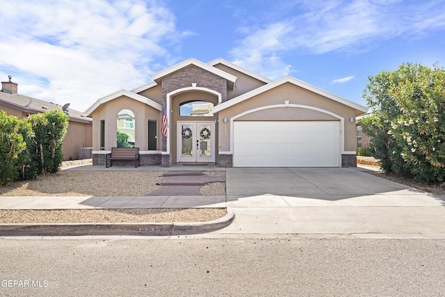 view of front of property with french doors, stucco siding, driveway, a garage, and stone siding