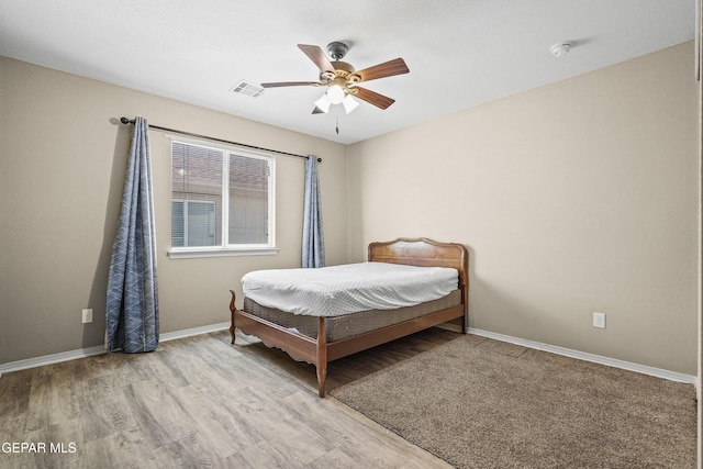 bedroom featuring ceiling fan, baseboards, visible vents, and wood finished floors