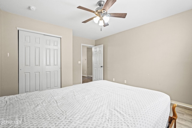 bedroom featuring a closet, baseboards, ceiling fan, and wood finished floors