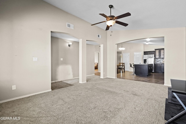 living area featuring carpet flooring, arched walkways, ceiling fan with notable chandelier, baseboards, and visible vents