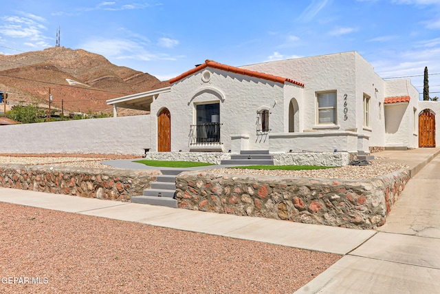 mediterranean / spanish home with stucco siding, a mountain view, fence, and a tiled roof