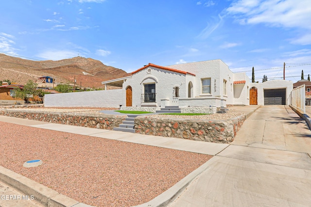 mediterranean / spanish-style house with an outbuilding, a garage, a mountain view, concrete driveway, and stucco siding